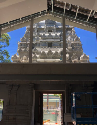 A construction view with large windows showing a temple's detailed exterior against a blue sky.